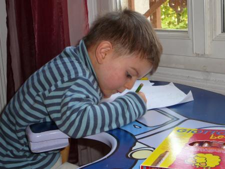 Liam s'applique pour dessiner un soleil...vert